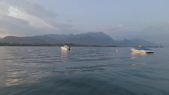 Flying over the lake water surface between motorboats, Lago di Garda aerial