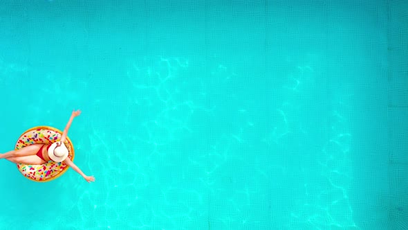 Aerial View of a Woman in Red Bikini Swimming on a Donut in the Pool