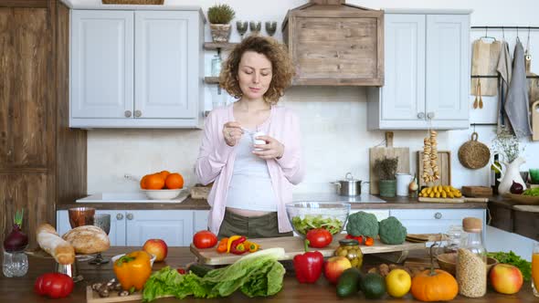 Pregnant Woman Eating Yogurt In The Kitchen. Healthy Food Concept
