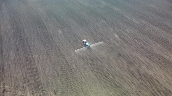 Aerial view tractor spraying seeds on land field