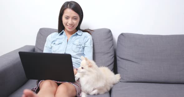 Woman use of laptop computer and be with her dog