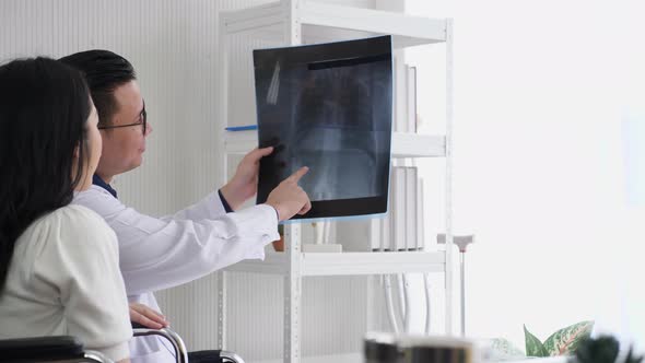 Male doctor holding x-ray film, talking, diagnosing female patient.