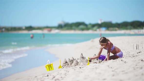 Little Girl at Tropical White Beach Making Sand Castle