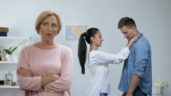 Angry Mother With Hands Crossed, Couple in Love on Background, Lack of Attention