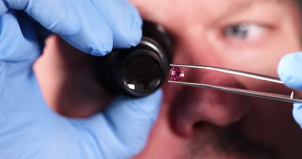 Jeweler Looking at Magnifying Glass at Pink Diamond on Tweezers Closeup  Movie Slow Motion