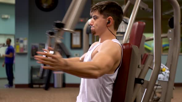 Closeup of young bodybuilder working the pec dec in a fitness club.
