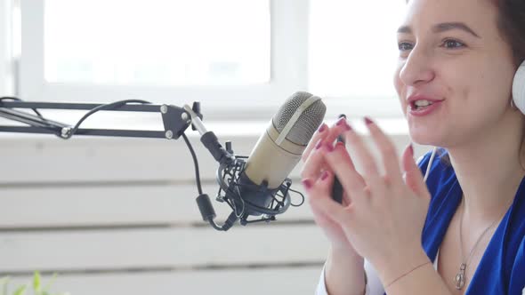 Concept of Streaming and Broadcasting. Young Cheerful Girl in the Studio Speaks Into a Microphone