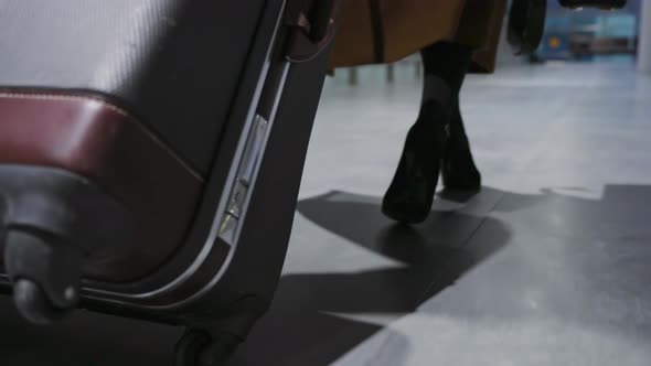 Back View of Female Legs and Suitcase Woman the Runs with a Suitcase Hurrying to Her Flight and