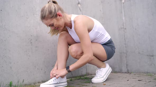 Cheerful Sportswoman Tying Laces on Sneakers