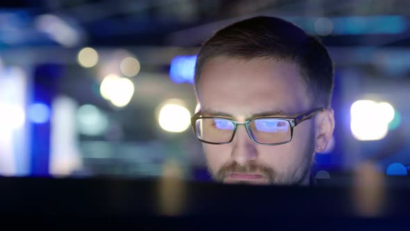 Close Up View of a Focused Man with Glasses in Front of a Computer
