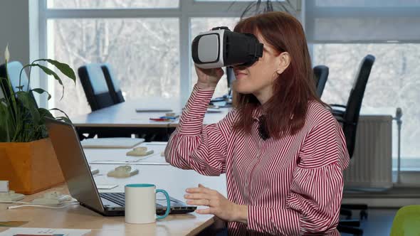 Mature Businesswoman Enjoying Using Virtual Reality Headset at Her Workplace