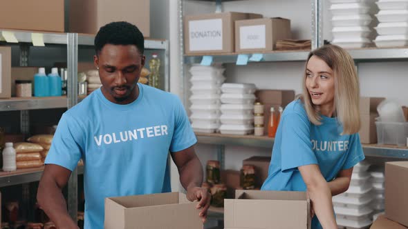 Two Diverse Volunteers Packing Donation Boxes