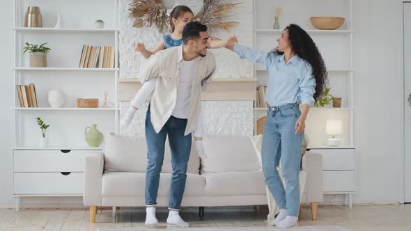 Hispanic Family Dancing at Home Living Room with Little Schoolgirl Daughter Celebrating Enjoying