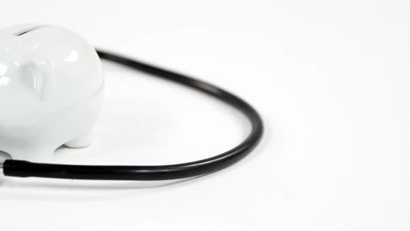 Stethoscope and piggy bank on white background