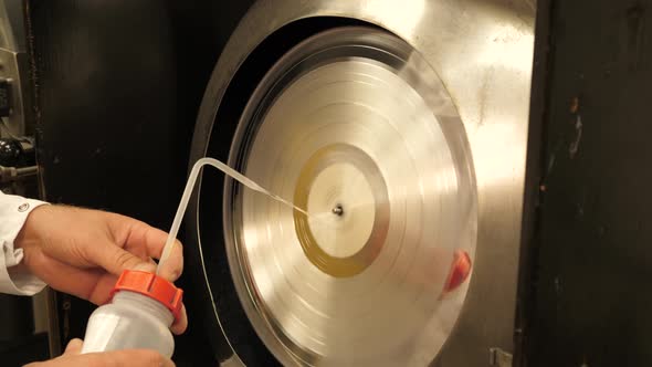 Vinyl record factory: Cleaning silver vinyl record mold with liquid