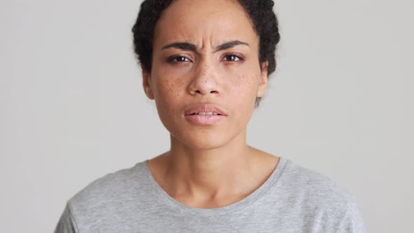 Displeased African woman in t-shirt showing silence gesture