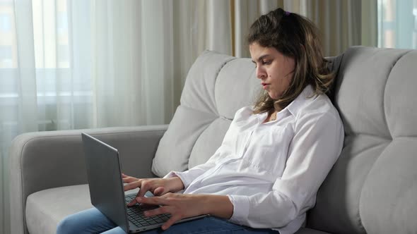 Disabled Woman Works on Computer Sitting on Sofa at Home