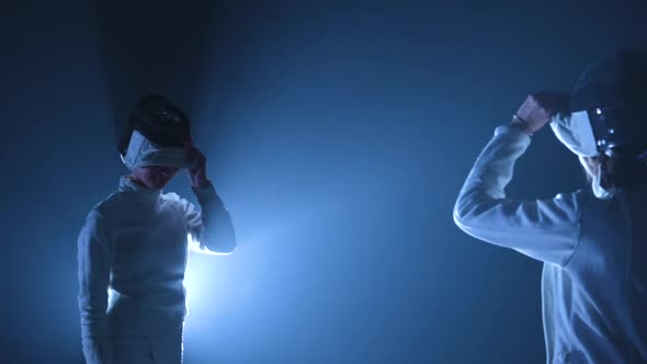 Two Young Female Fencers Take Off Their Fencing Masks Salute with Rapiers and Greet Each Other