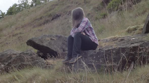 Woman sitting on a rock in rugged moorland