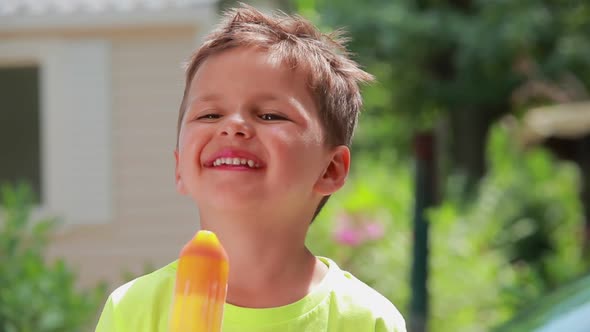 The Cute Cheerful Boy Is Eating Ice Cream Outdoors on the Sunny Day