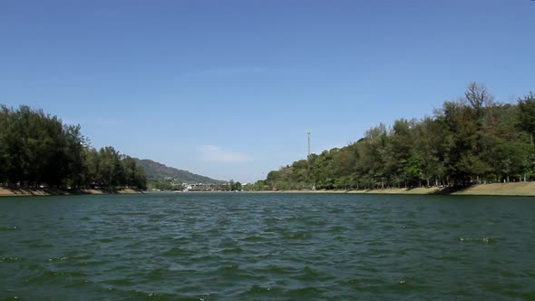 locked low angle shot of panoramic view of Nai Harn Lake on a breezy blue sky summer day, no people,