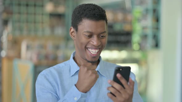 Excited Young African Man Celebrating on Smartphone 