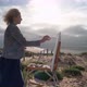 Middleaged European Woman Artist Paints a Picture with Paints Overlooking the Sea - VideoHive Item for Sale