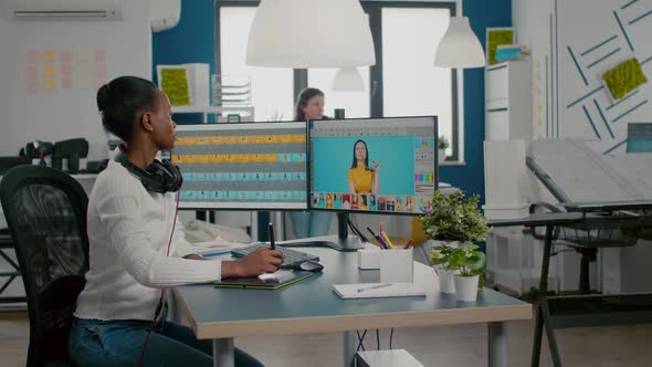 Black Retoucher Woman Analysing Images on Computer with Two Monitors