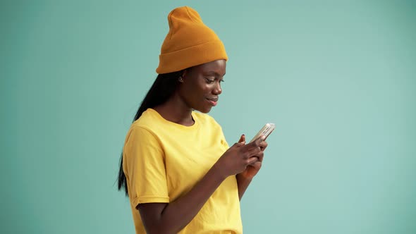 Smiling African woman texting by phone