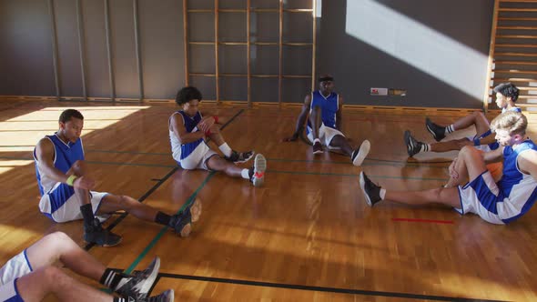 Diverse male basketball team wearing blue sportswear and stretching