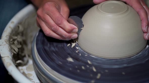 Pot maker hands are crafting pottery, slow motion video sequence capturing rotation of bowl.