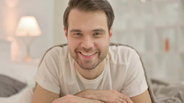 Close Up Young Man Smiling at Camera, in Bed