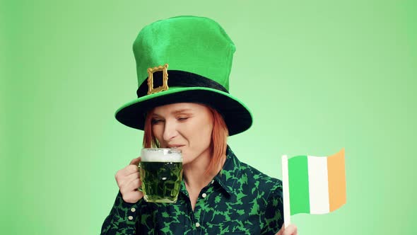 Happy woman with Irish flag drinking beer