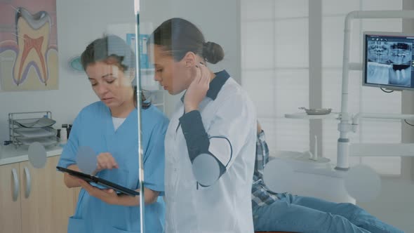 Dentist and Assistant Analyzing Modern Tablet Screen