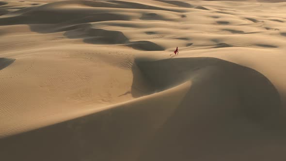  Aerial View of a Lonely Woman Walking Through the Massive Sand Dunes at Sunset