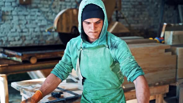 Worker man measures stone plate and breaks it with a hammer in the factory.