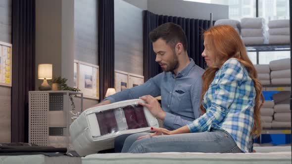 Couple Choosing Orthopedic Mattress at Furniture Store Together