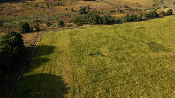 Aerial view, drone view a SUV driving along a dirt road, black suv car driving through a gravel road