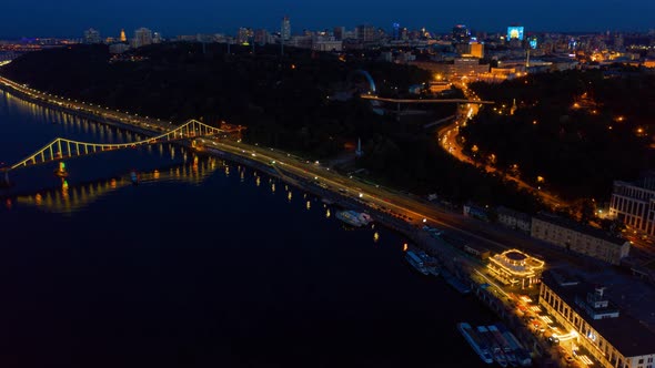 Night Kiev Hyperlapse. Colorful Pedestrian Bridge on the Banks of the Dnieper. Aerial Footage