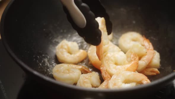 Unrecognizable cook frying prawns in pan with hot oil