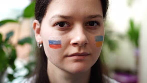 A Sad Young RussianUkrainian Girl with the Flag of Ukraine and Russia on Her Face is Shaking Head NO