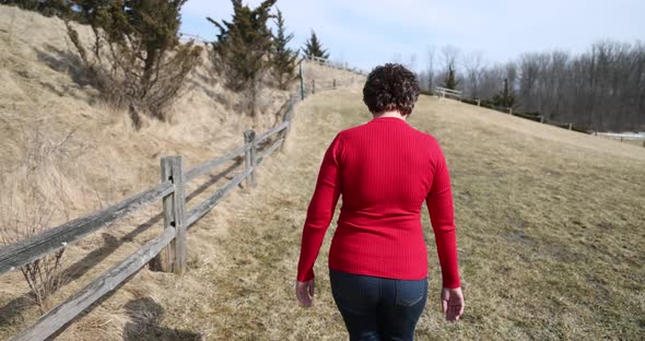 Woman in red top and jean walking.