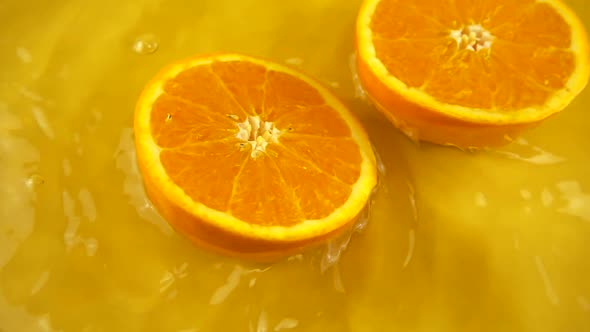 Rotating segment of a ripe and juicy orange on an orange background. Slow motion.