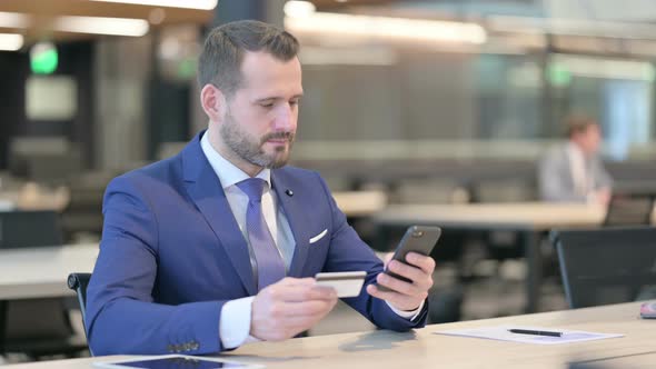 Middle Aged Businessman Excited By Online Shopping Success on Smartphone