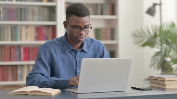 Young African Man Celebrating Success While Using Laptop in Office