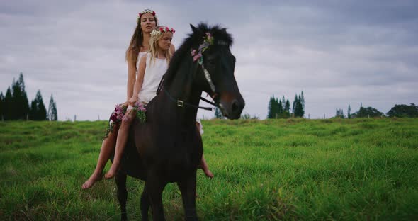 Happy woman and flower girl riding horse together