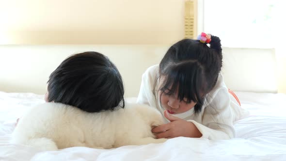 Cute Asian Children Playing With Puppy On Bed