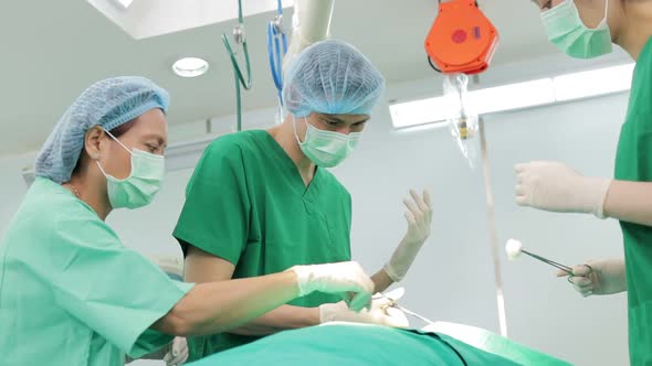 Professional team of Asian surgeons Perform surgery on a patient lying on a bed in a hospital