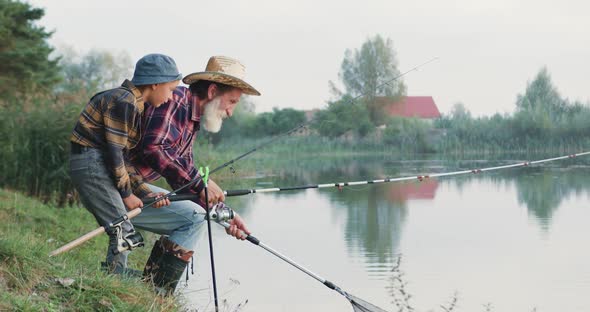 Senior Fishman Fishing Together with His Joyful Handsome Grandchild Using Fishing Rods