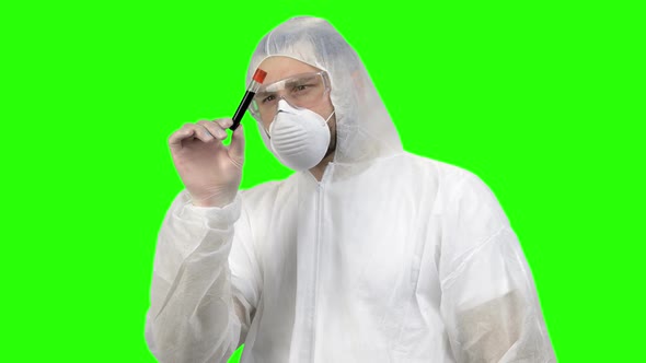 Researcher or Scientist in Protective Clothing Looking at Blood Test Tube